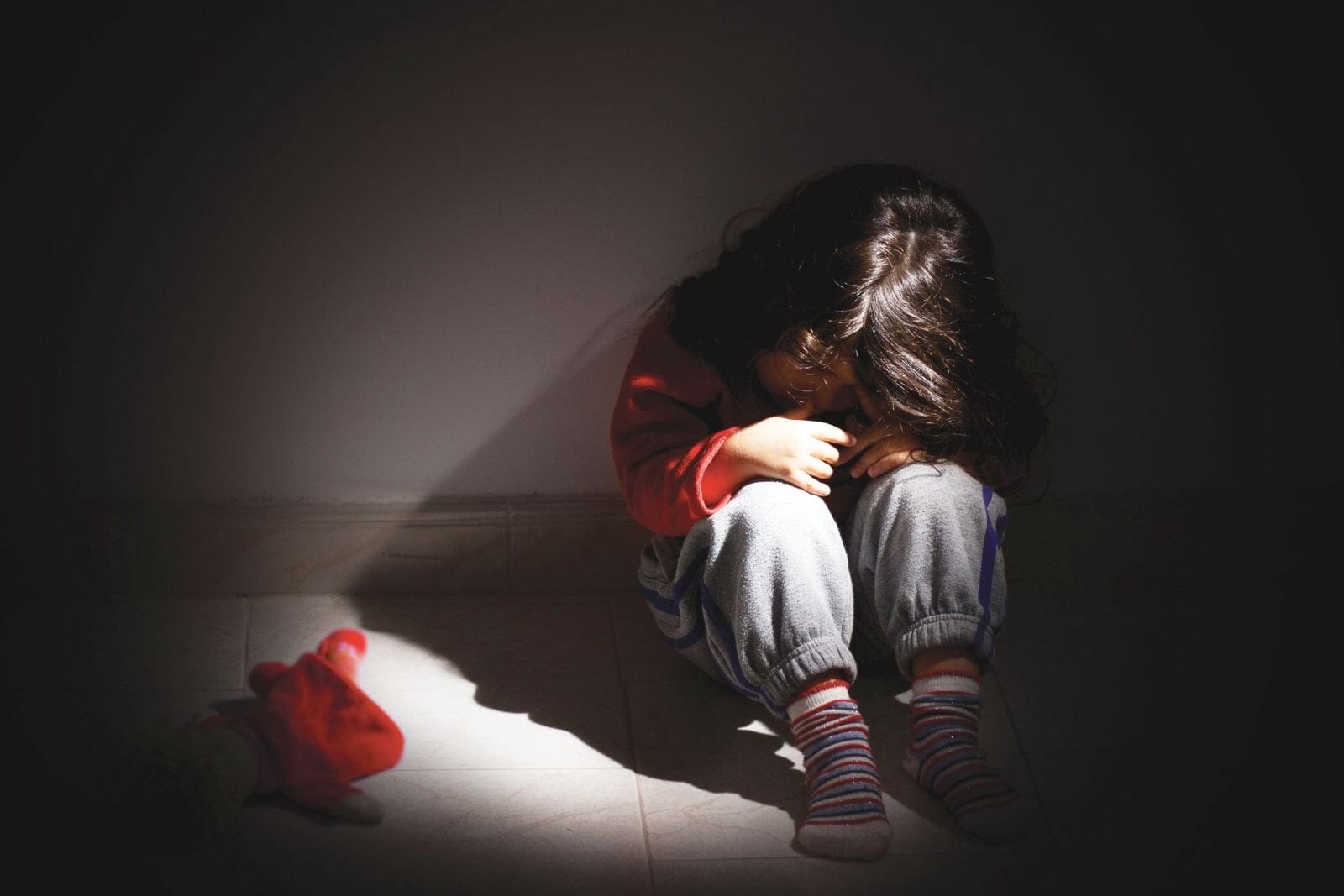 A child sitting in dark struggling with the symptoms of PTSD